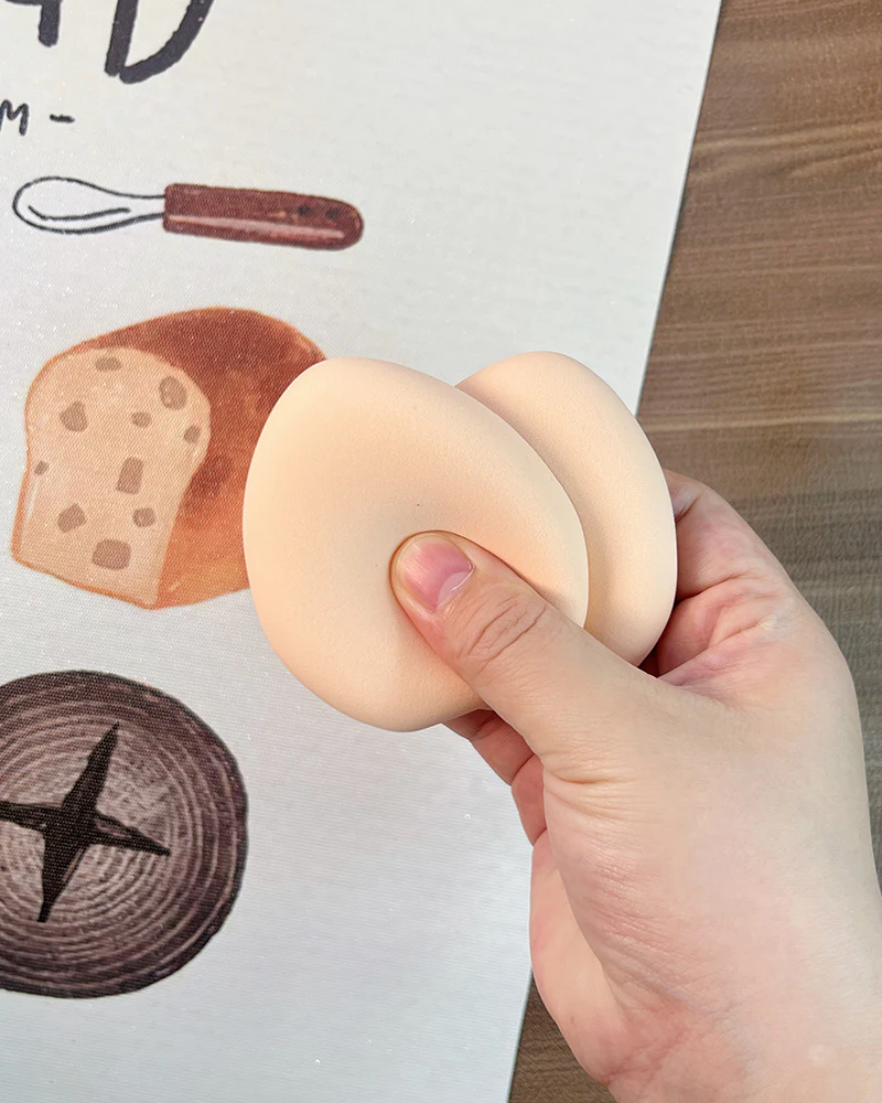 Two unbranded makeup puffs shown by hand